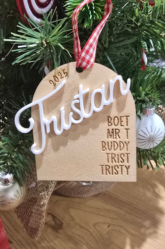 Wooden ornament with 'Tristan' and other names on a Christmas tree.