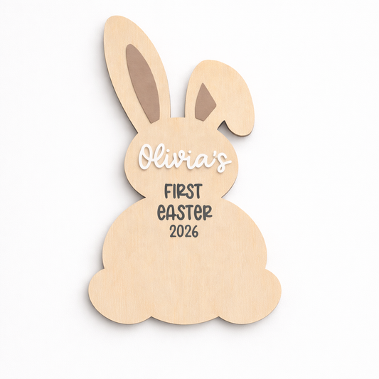 Wooden bunny-shaped decoration with 'Olivia's First Easter 2026' text on a white background