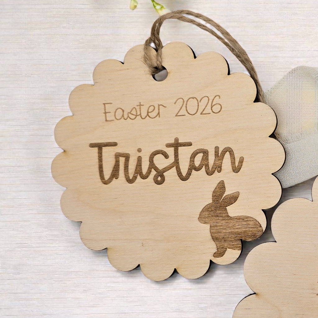 Two wooden Easter tags with engraved text and bunny illustrations on a light background with flowers and eggs.