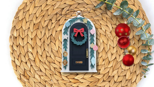 Decorative door ornament with wreath and bow on a woven mat with Christmas decorations.
