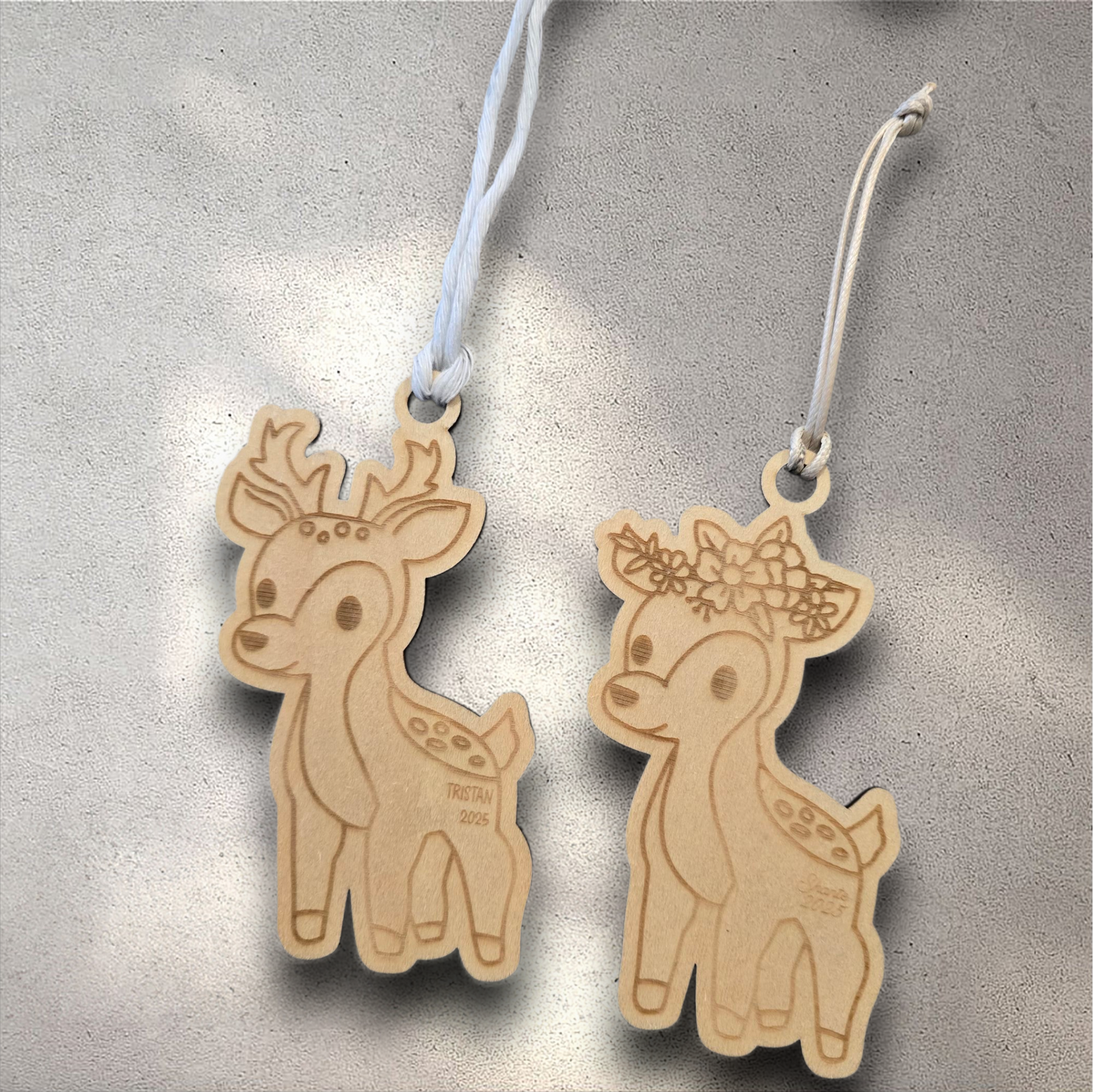 Two wooden deer ornaments with decorative elements on a textured surface