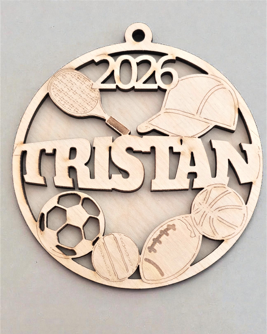 Decorative metal ornament with sports-themed elements and '2026 Tristan' text on a gray background