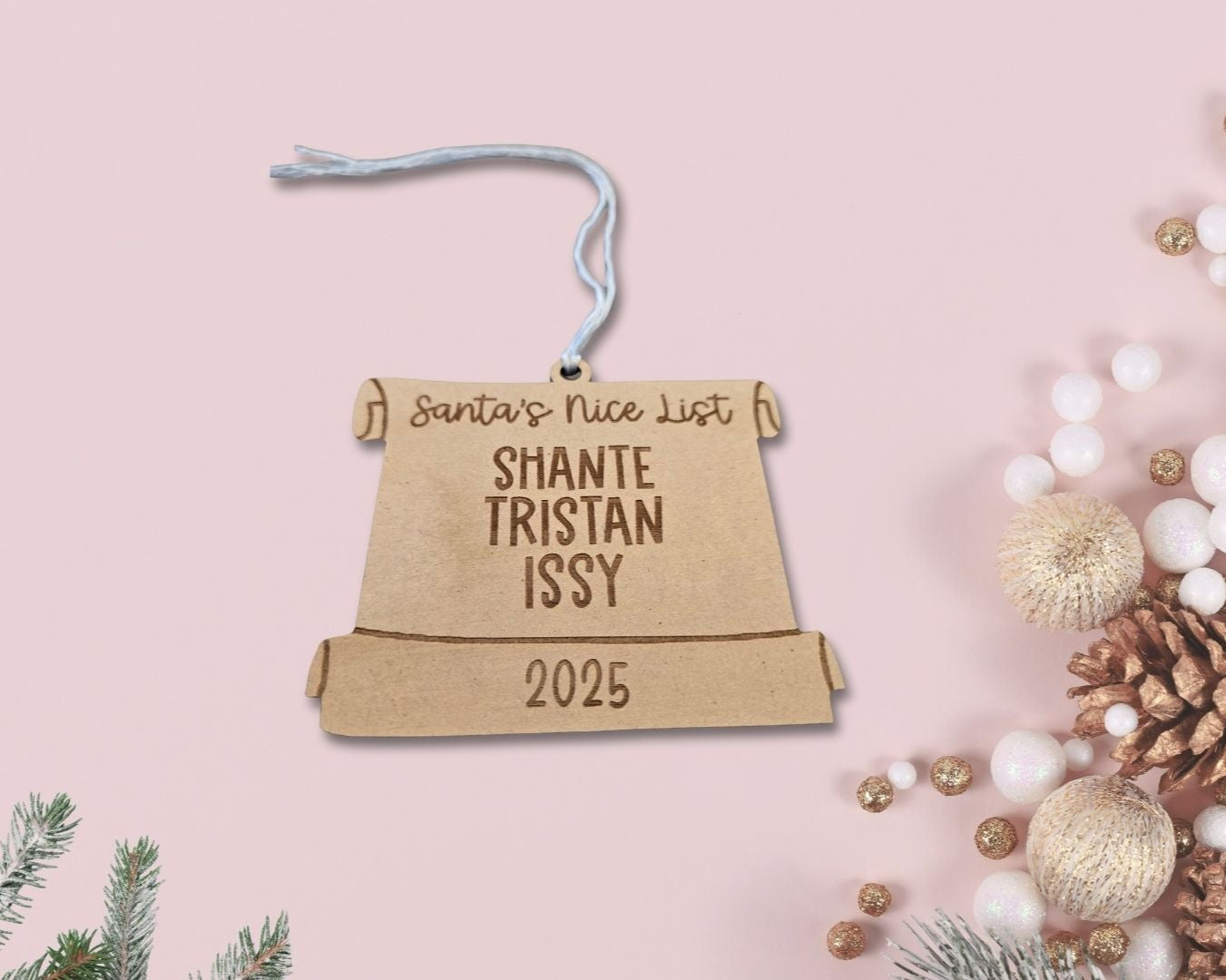 Personalized Christmas ornament on a pink background with festive decorations