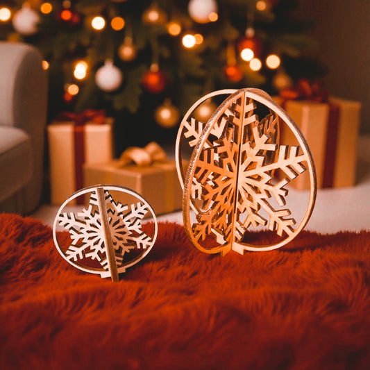 Wooden snowflake decorations on a red surface with a blurred Christmas tree and presents in the background.