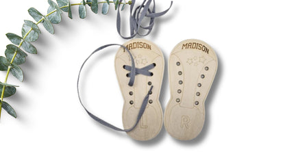 Pair of Madison baby shoes on a white background with greenery