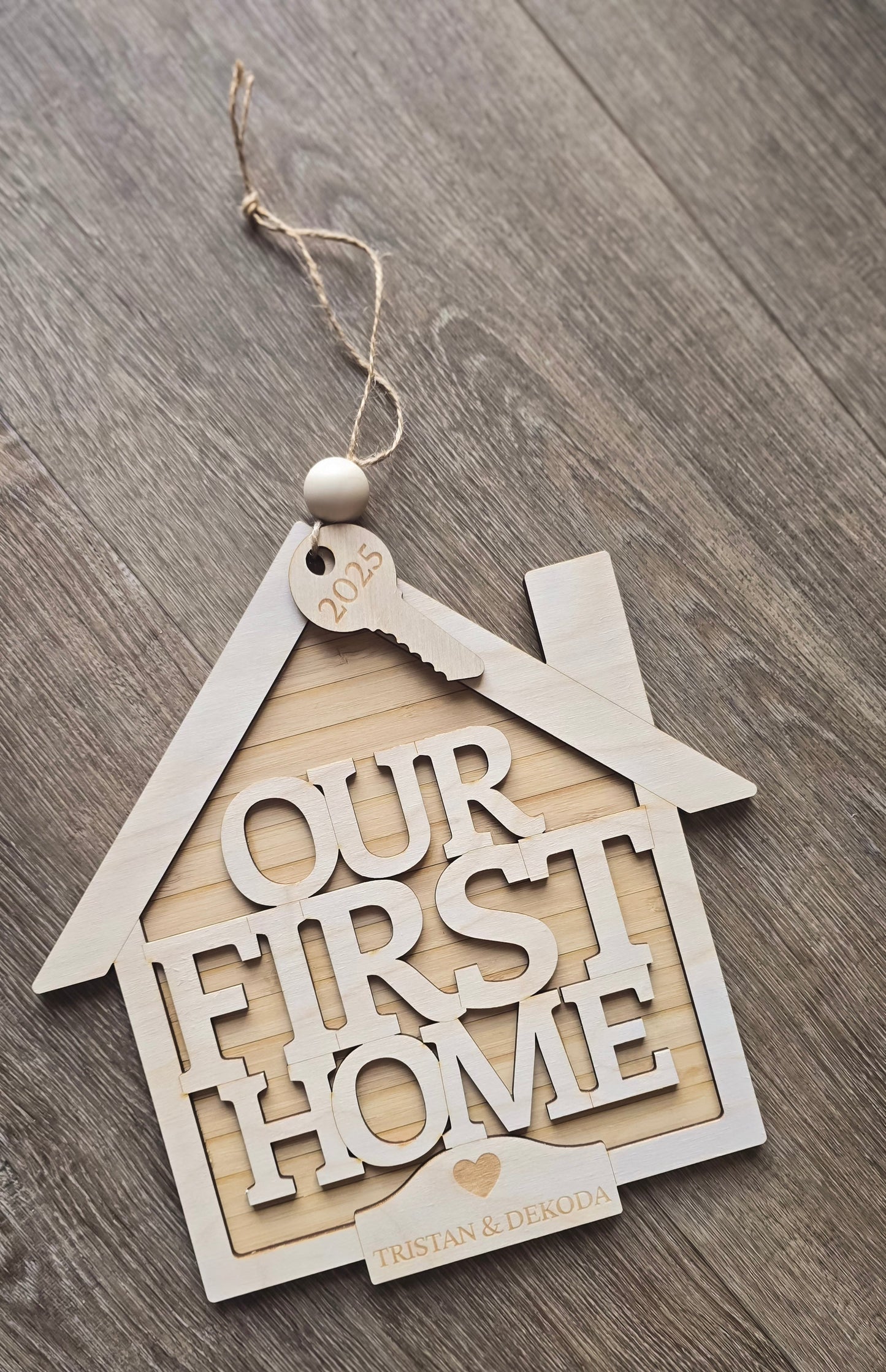 Decorative house-shaped sign with 'Our First Home' text on a wooden surface