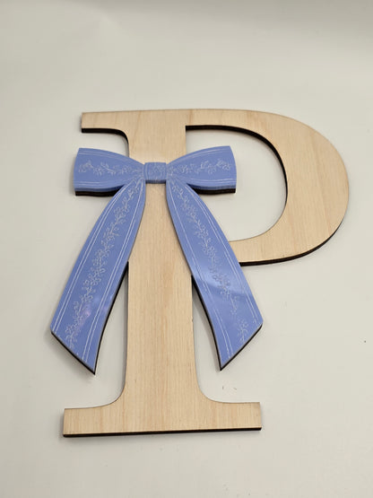 Wooden letter 'D' with a blue bow on a white background