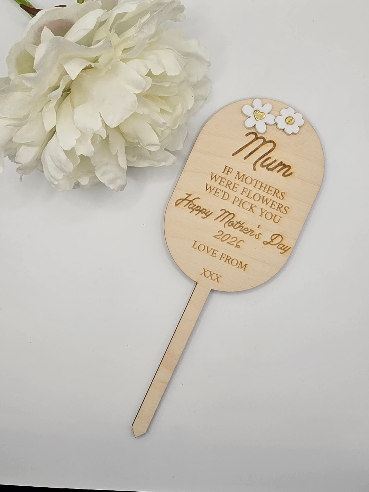 Wooden paddle with engraved text and flowers on a white background
