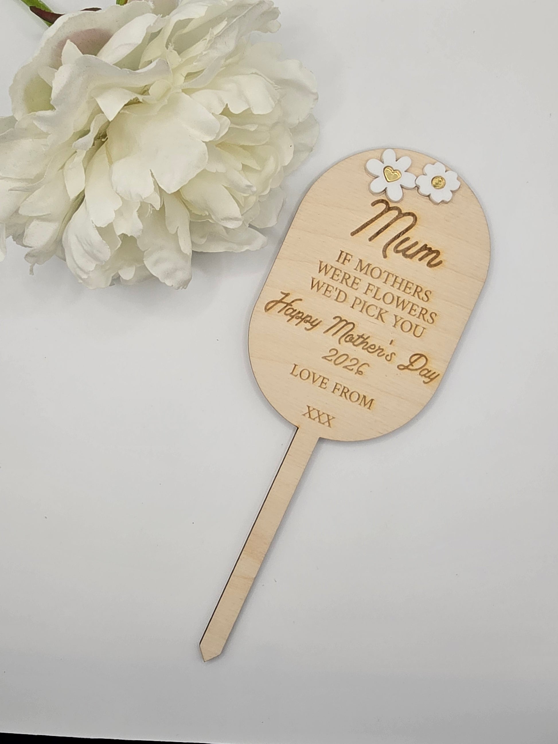 Wooden paddle with engraved text and flowers on a white background