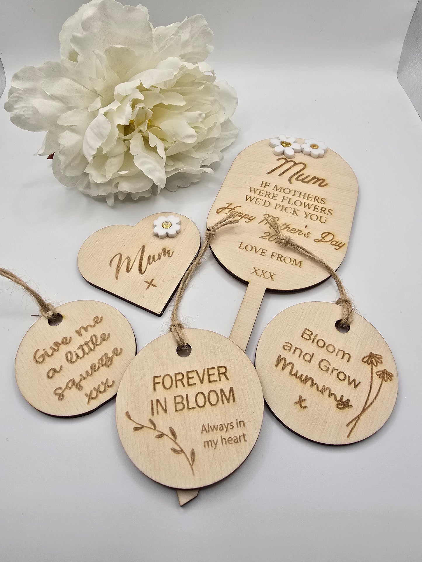 Wooden tags with engraved messages and a white flower on a light background