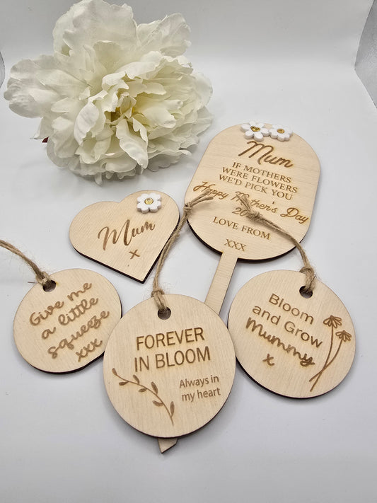 Wooden tags with engraved messages and a white flower on a light background