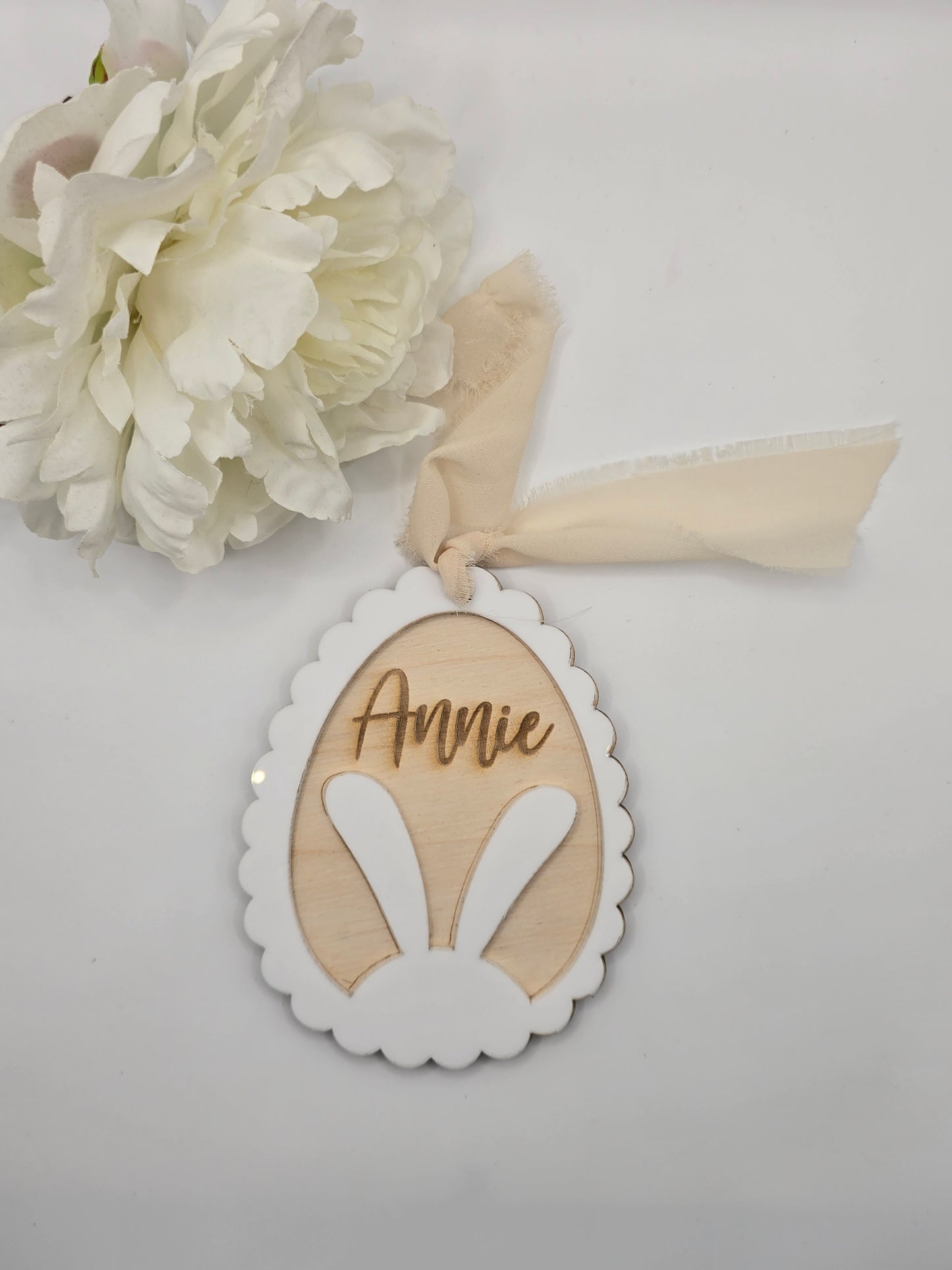 Decorative item with a ribbon and floral element on a light gray background
