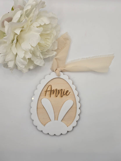 Decorative item with a ribbon and floral element on a light gray background