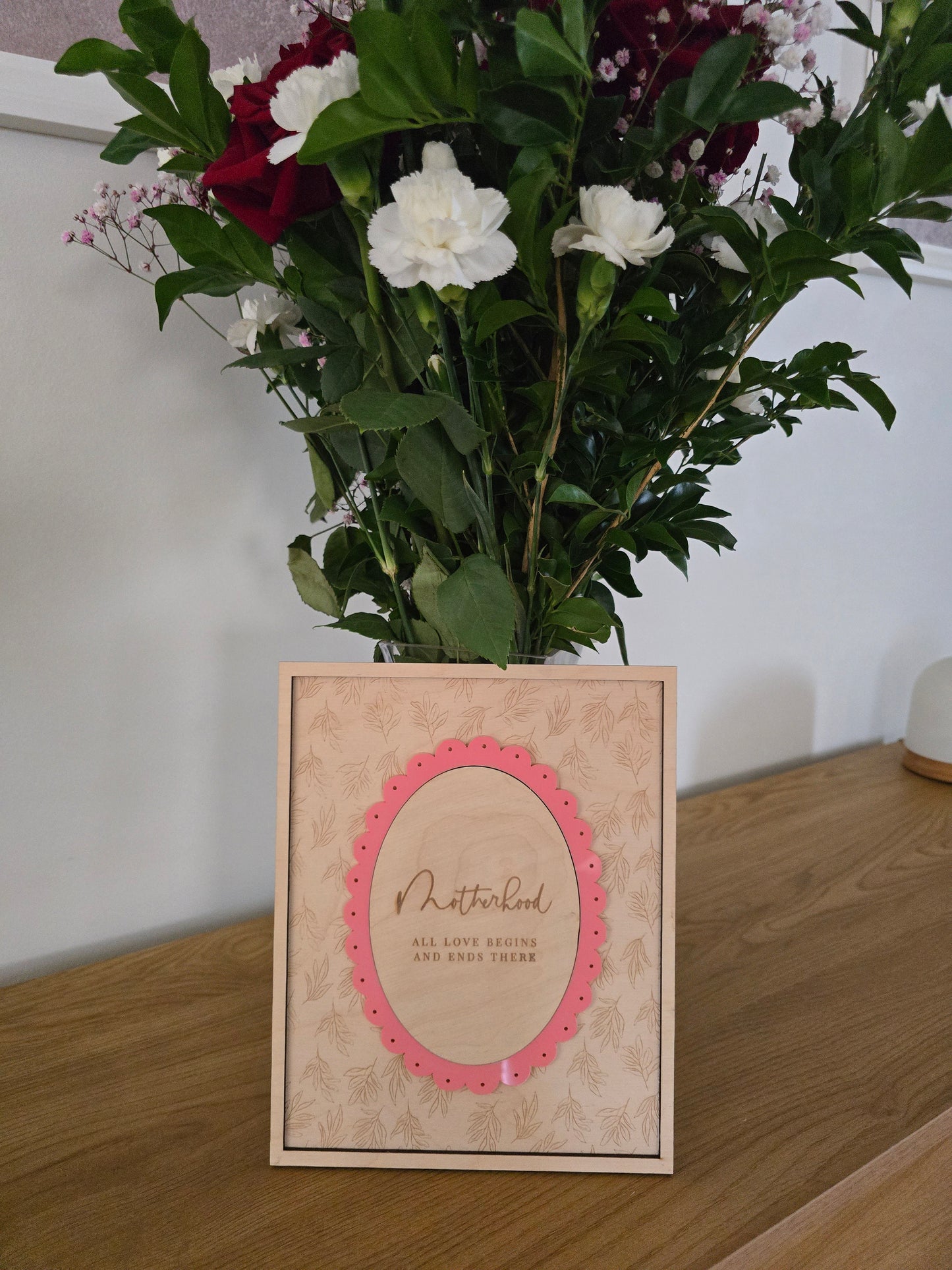 Floral arrangement with a decorative card on a wooden surface