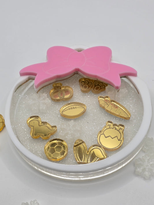 Gold decorative items on a white circular base with a pink butterfly-shaped object.