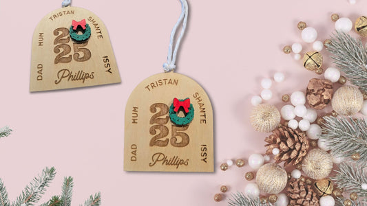Personalized Christmas tags with names and year on a pink background with festive decorations.