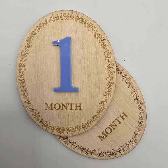 Two wooden age markers with '1 month' text on a gray background