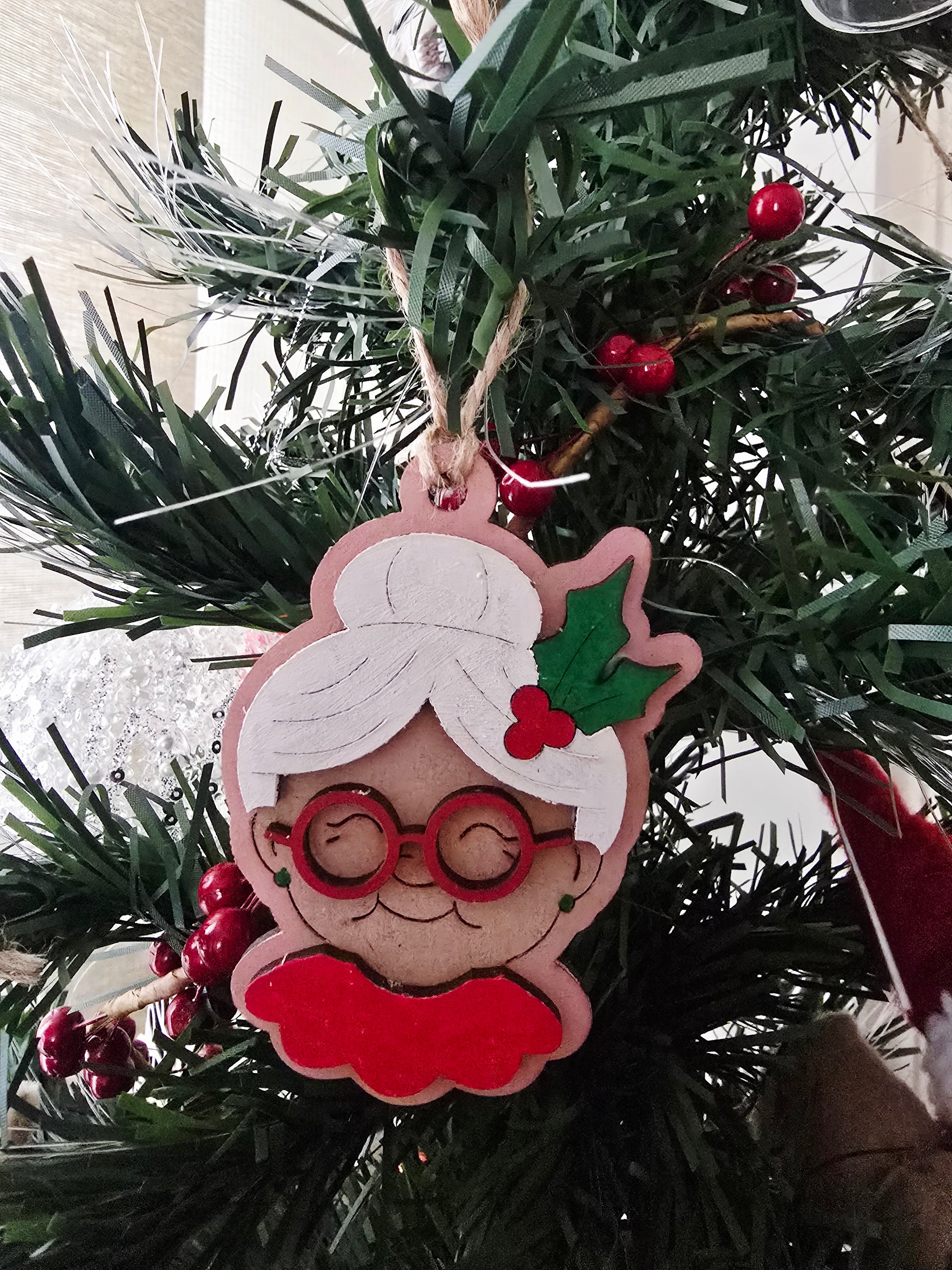 Christmas ornament of a character with glasses and a red skirt hanging on a tree.