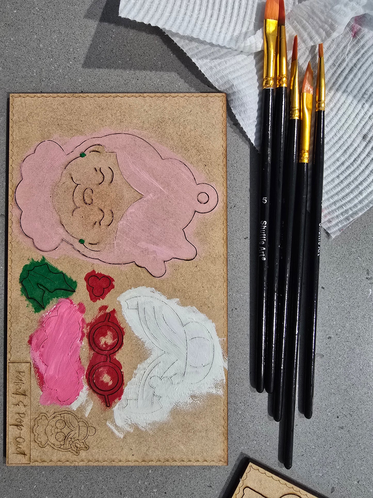 Card with cut-out shapes and paintbrushes on a textured surface