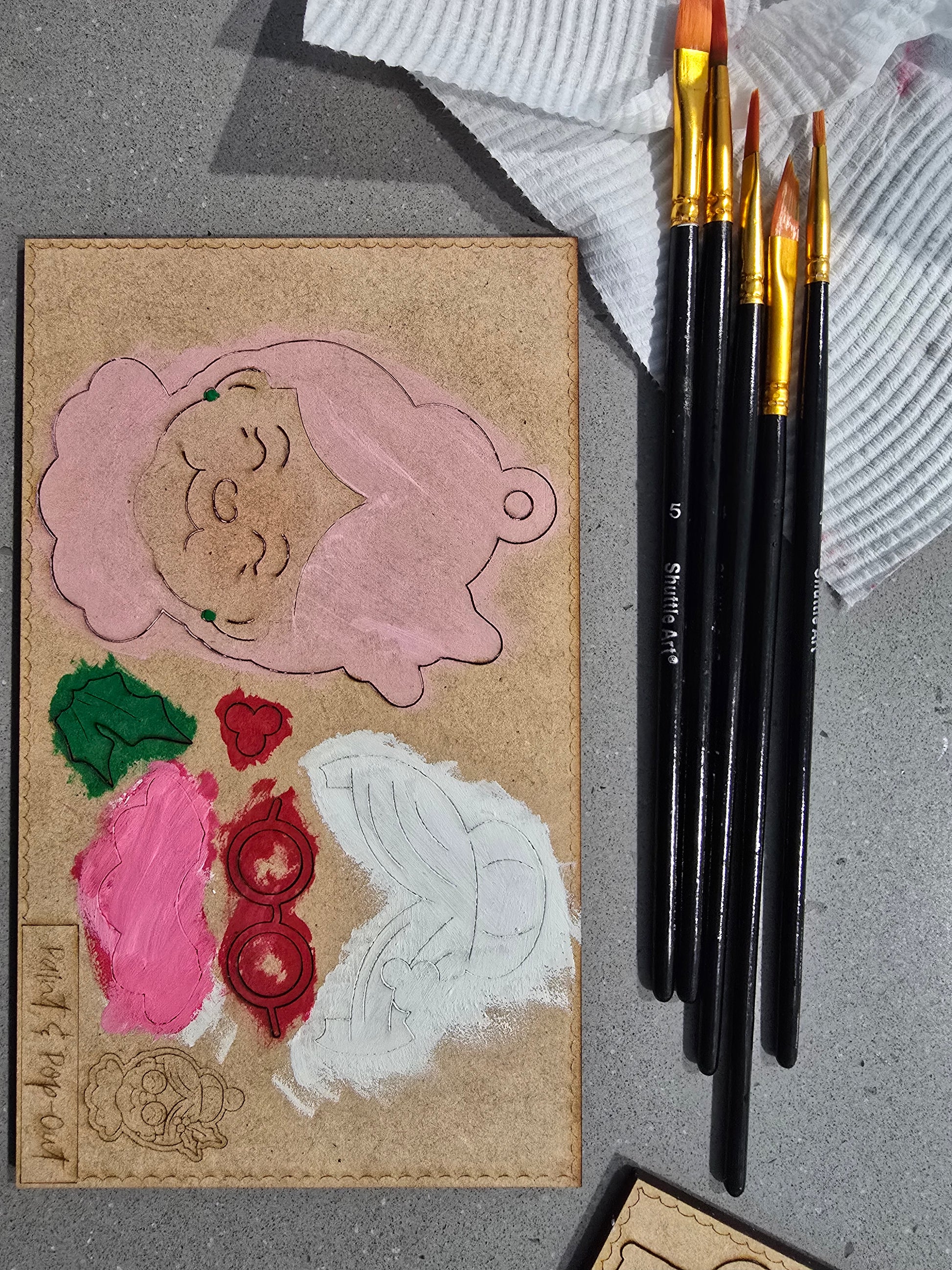 Card with cut-out shapes and paintbrushes on a textured surface