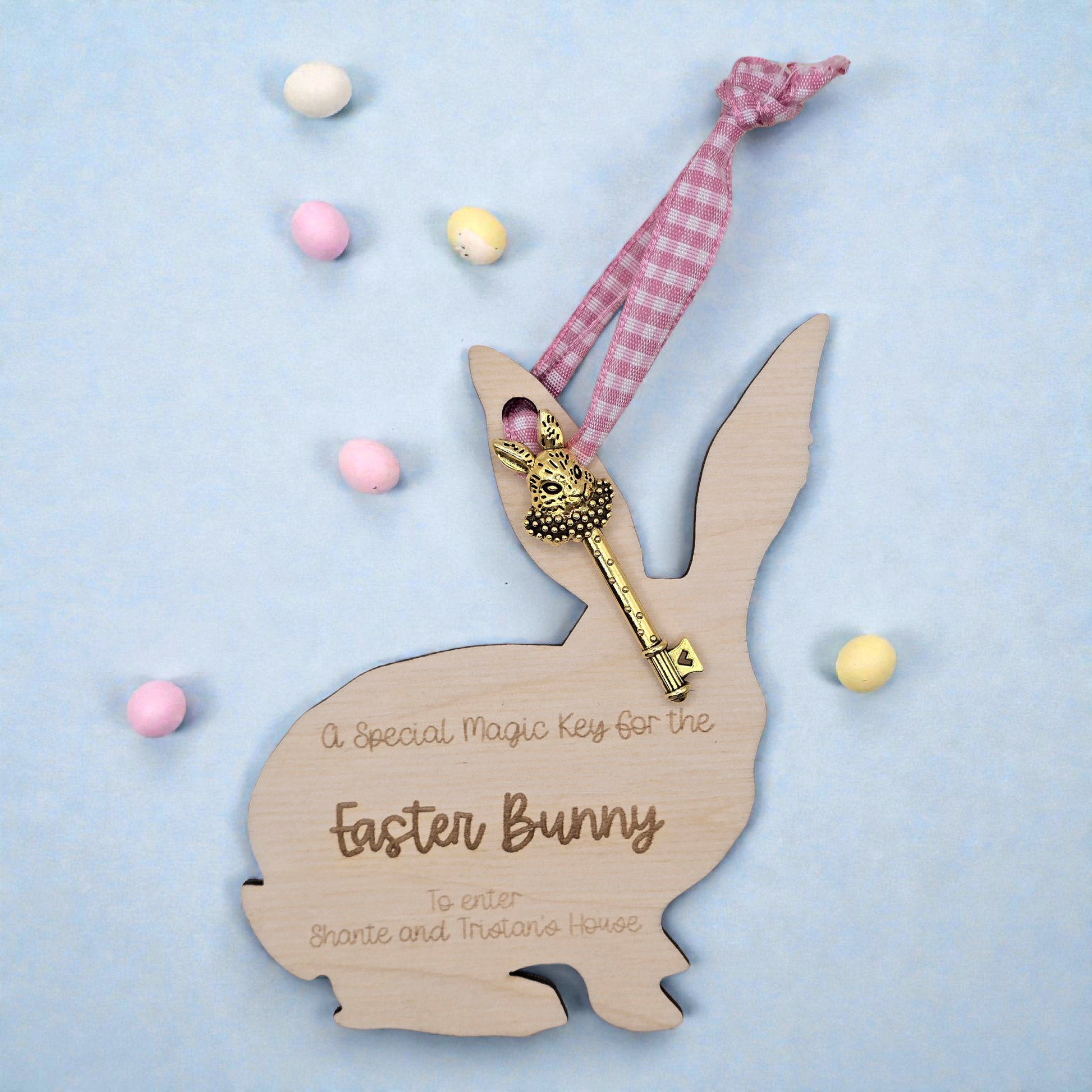 Wooden Easter bunny with a key and text on a light blue background with Easter eggs.
