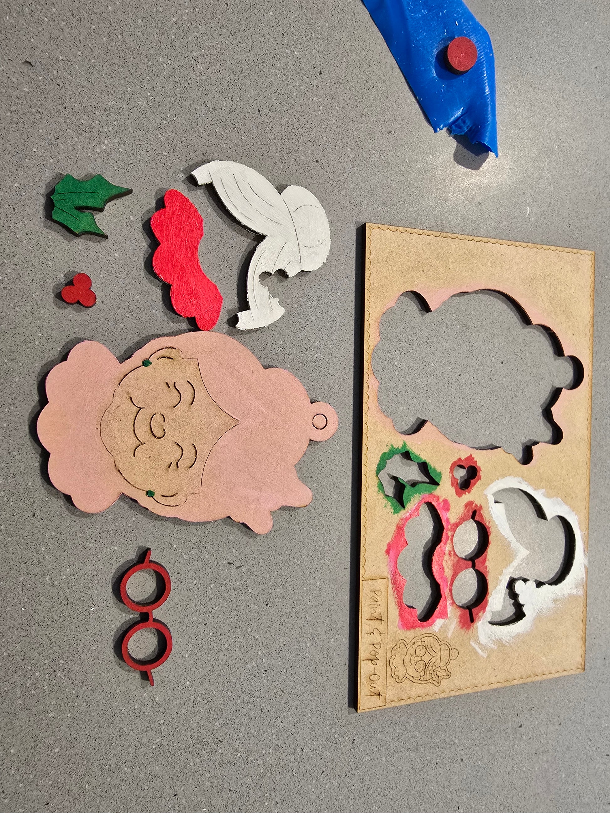 Cardboard cutouts of decorative shapes with a cutting tool on a gray surface