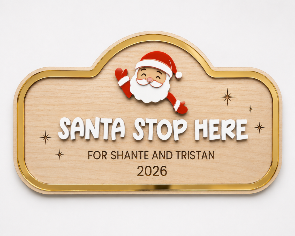 A personalized wooden plaque with a gold border, featuring a cartoon Santa Claus illustration above the text 'SANTA STOP HERE FOR SHANTE AND TRISTAN 2026' on a light gray background.
