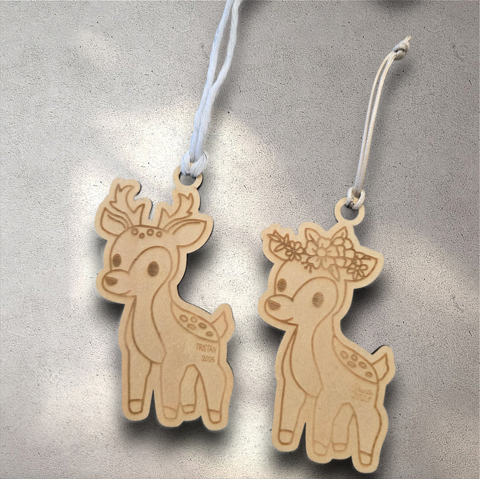 Two wooden deer ornaments with decorative elements on a textured surface