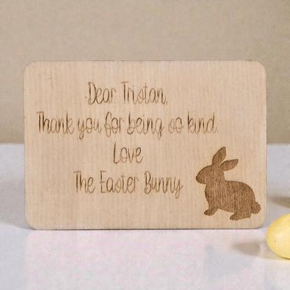 Wooden card with engraved message from the Easter Bunny on a light background