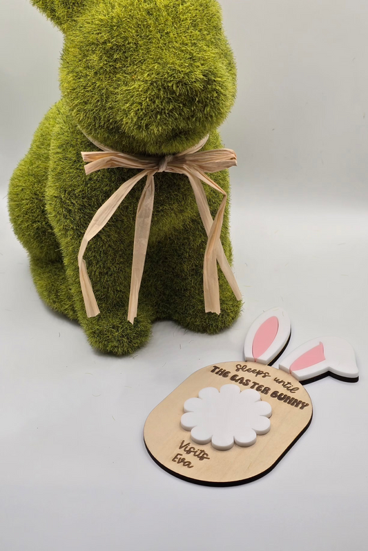 Green textured bunny with a beige bow, wooden plaque, and rabbit ears on a white background