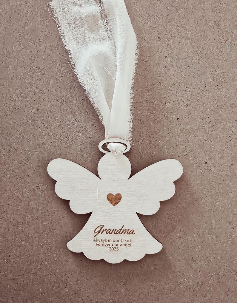 White angel-shaped ornament with a heart and text on a beige background