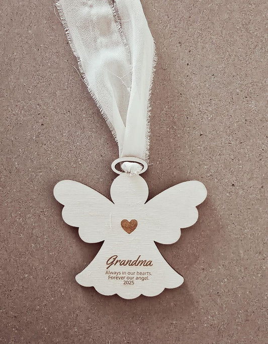 White angel-shaped ornament with a heart and text on a beige background
