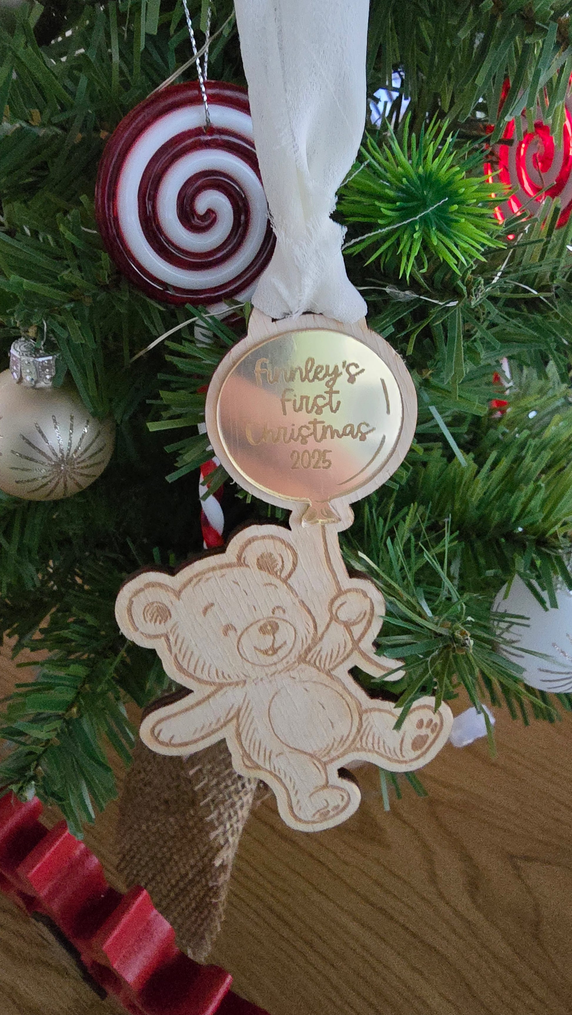 Decorative Christmas ornament with teddy bear and text on a tree