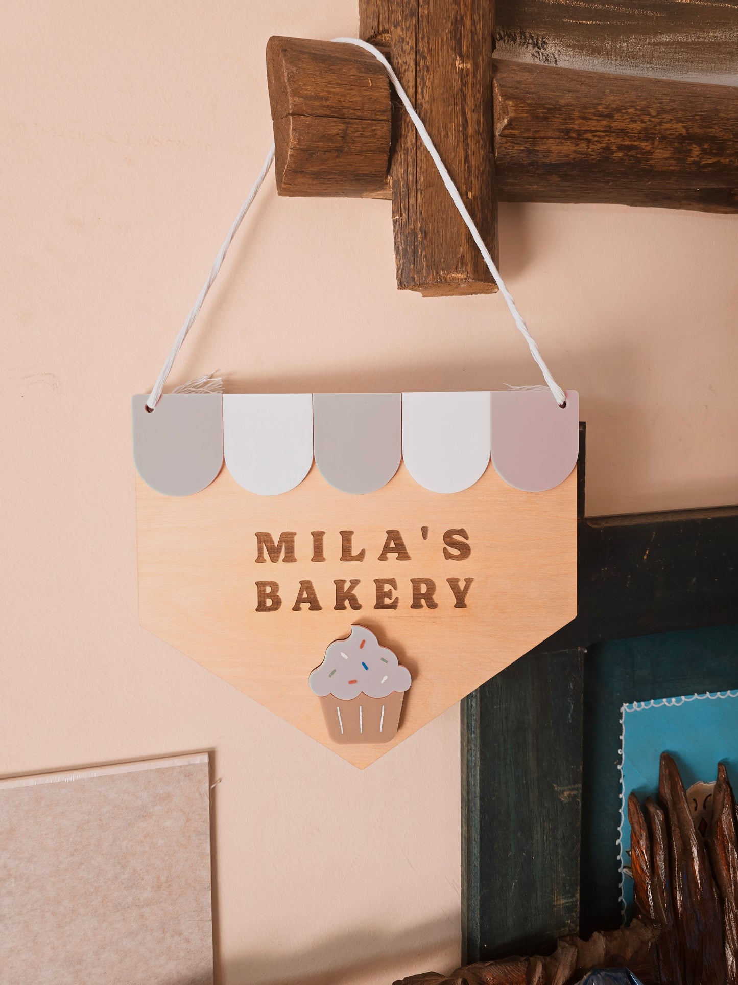 Custom wooden “Name’s Bakery” kids playroom sign by PeppaTree Designs, featuring colorful painted lettering on natural wood background.