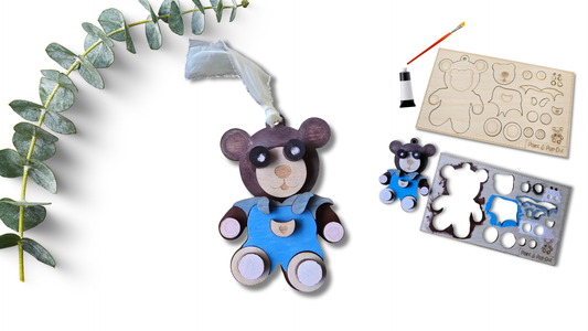 Wooden bear toy with paintbrushes and paint can on a white background